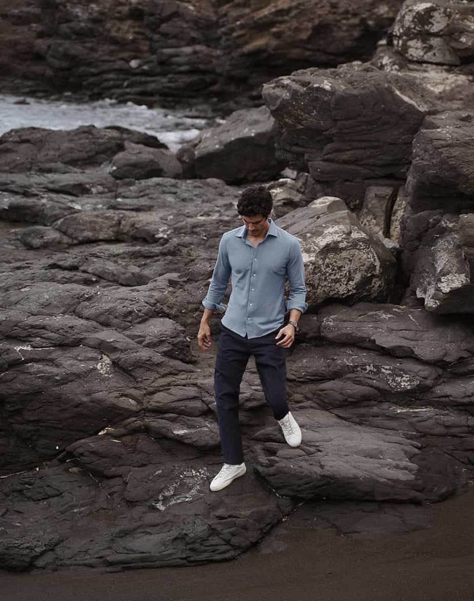 man walking on a rocky shore, modeling Luca Faloni clothes 