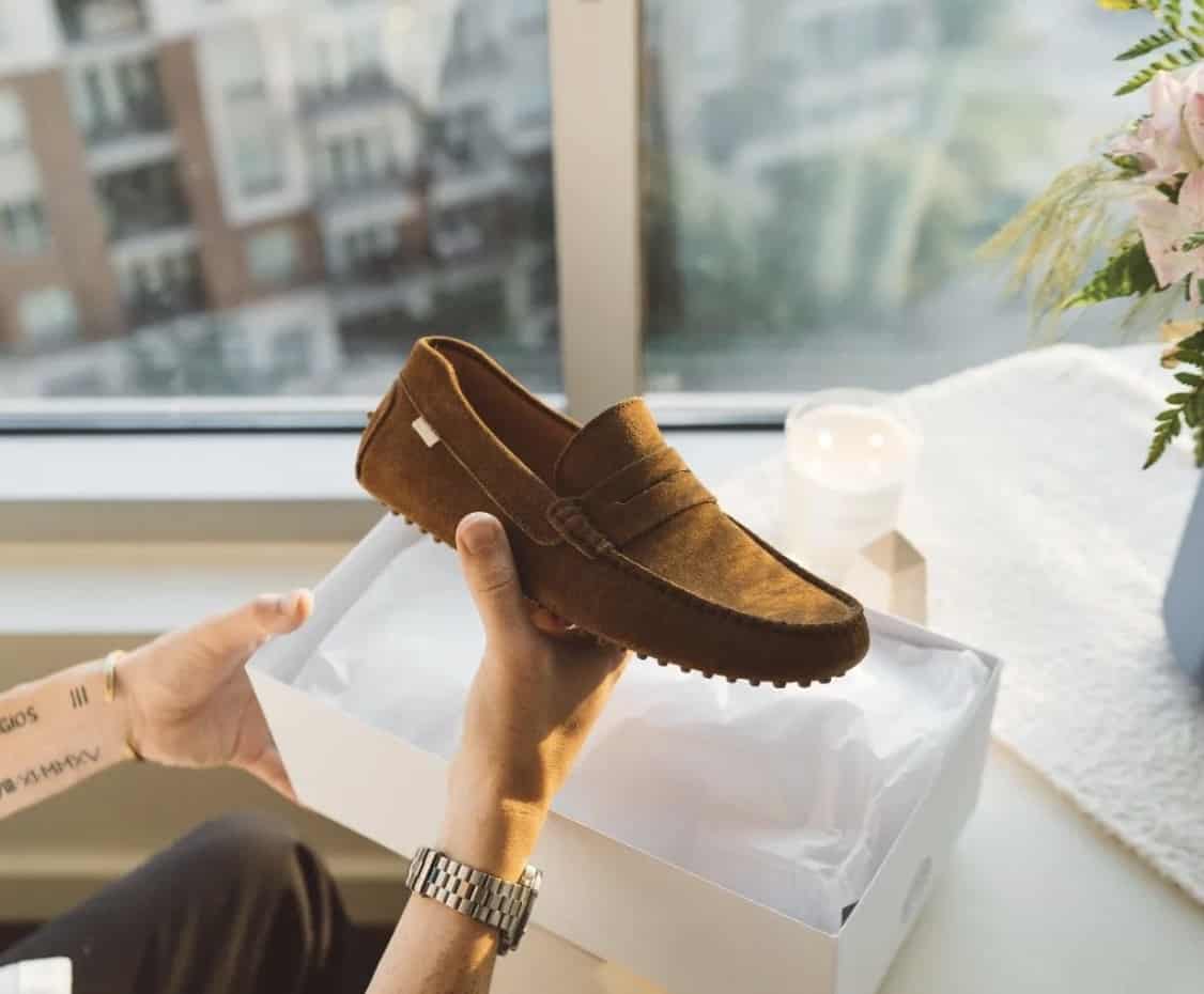 man holding up a suede driver out of the box