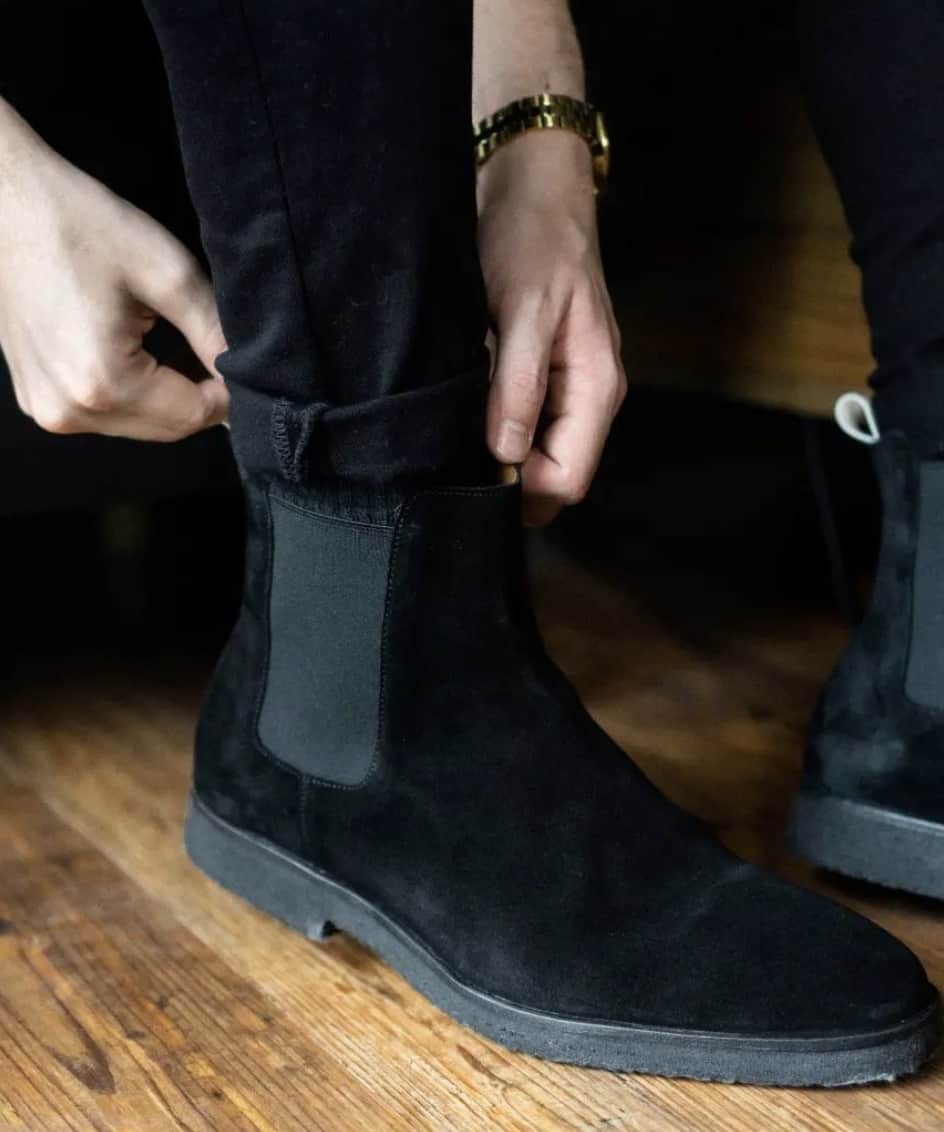 man putting on a suede black chelsea boot