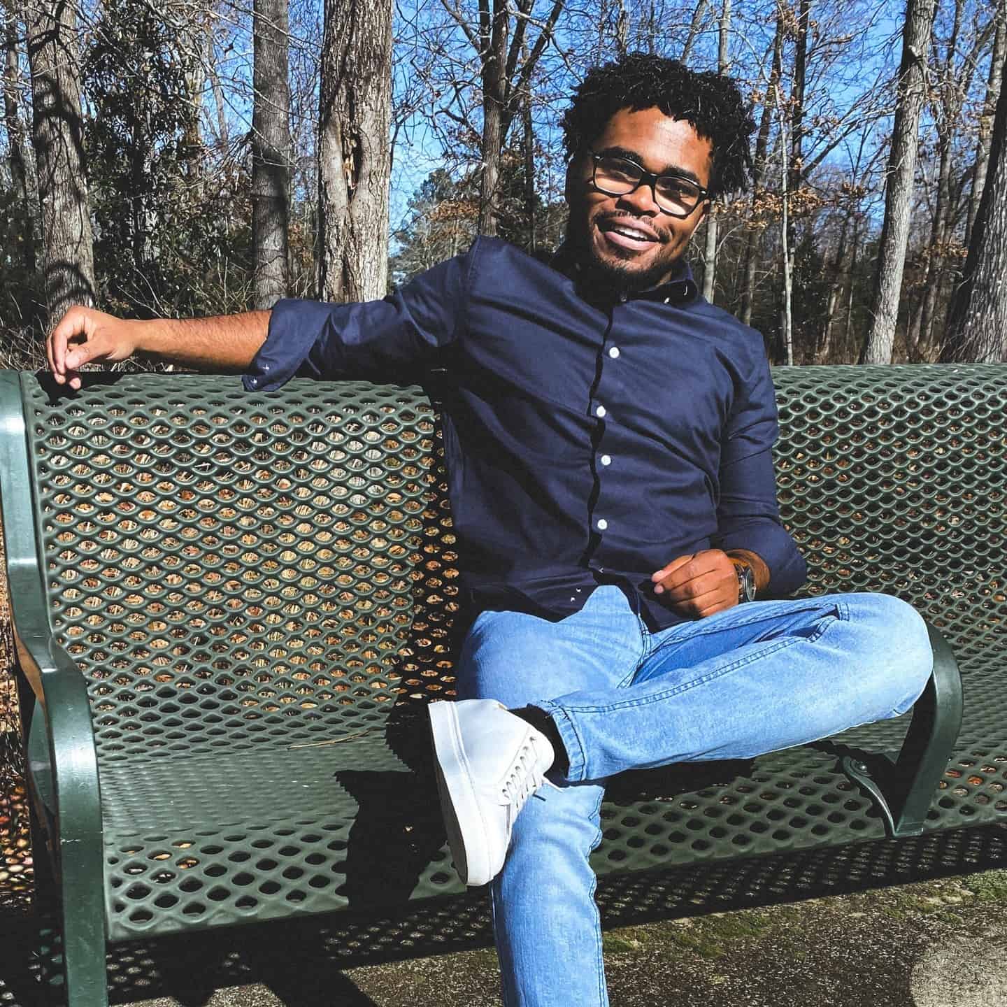 man in a blue shirt sitting on a metal bench