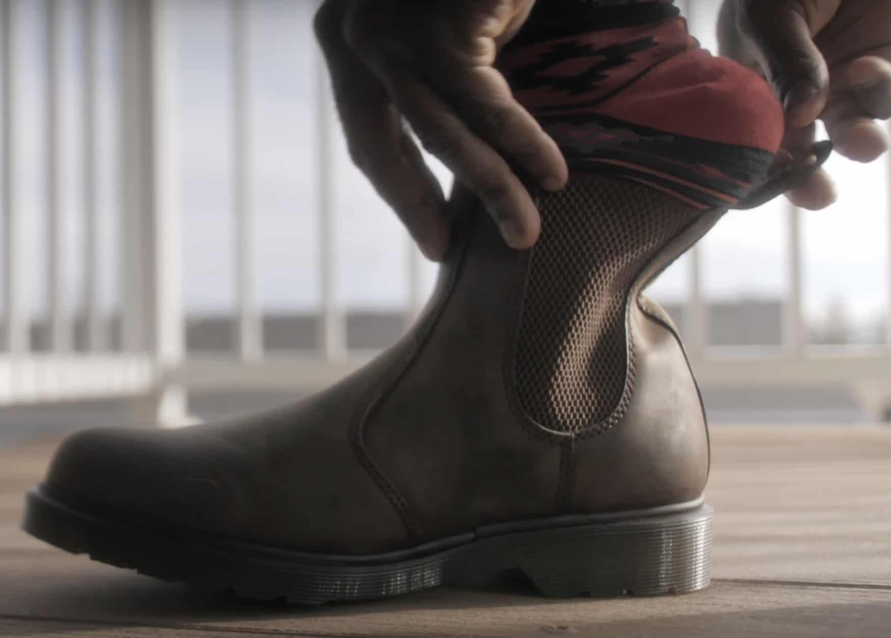 Man putting on a brown leather chelsea boot 