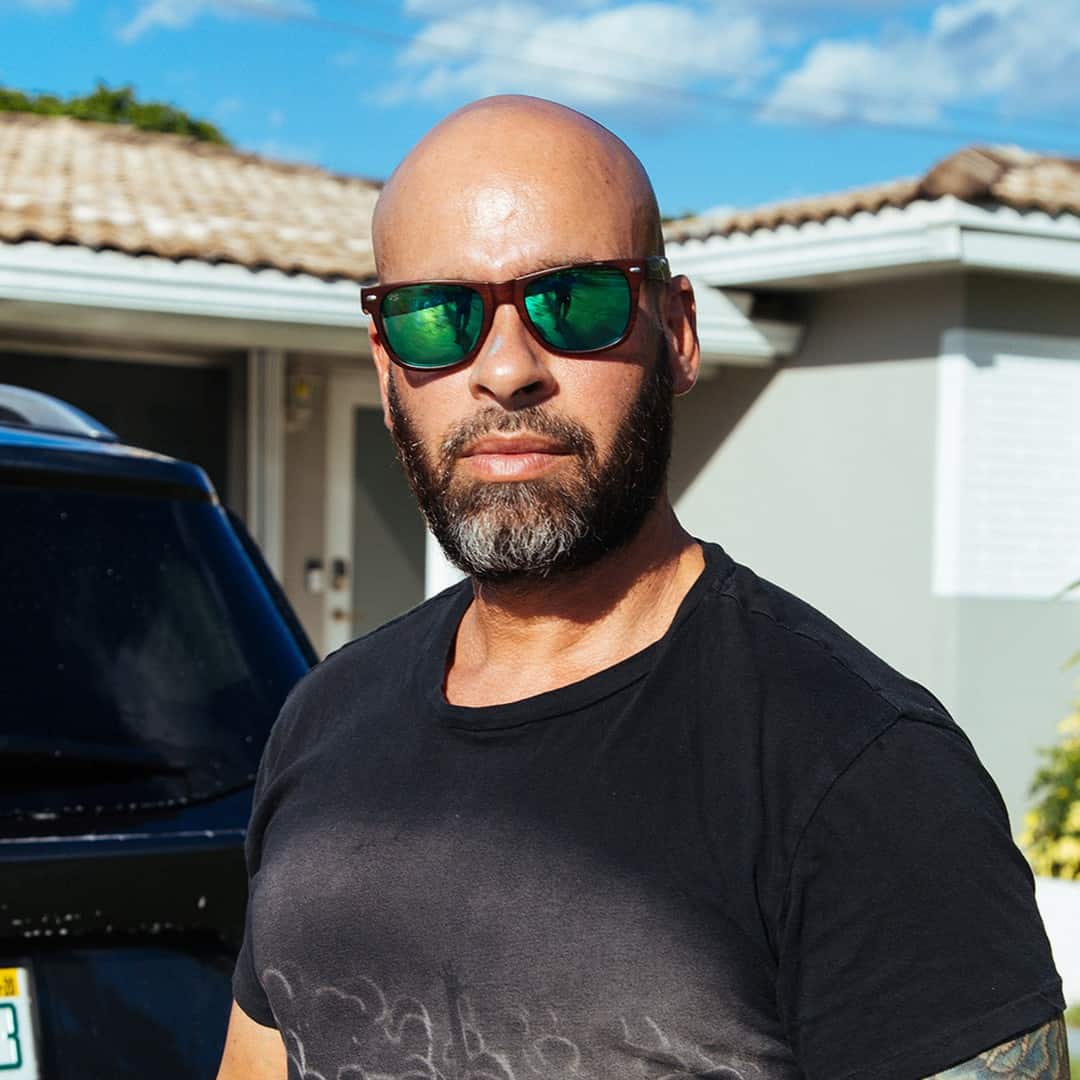 bald man wearing riviera shades