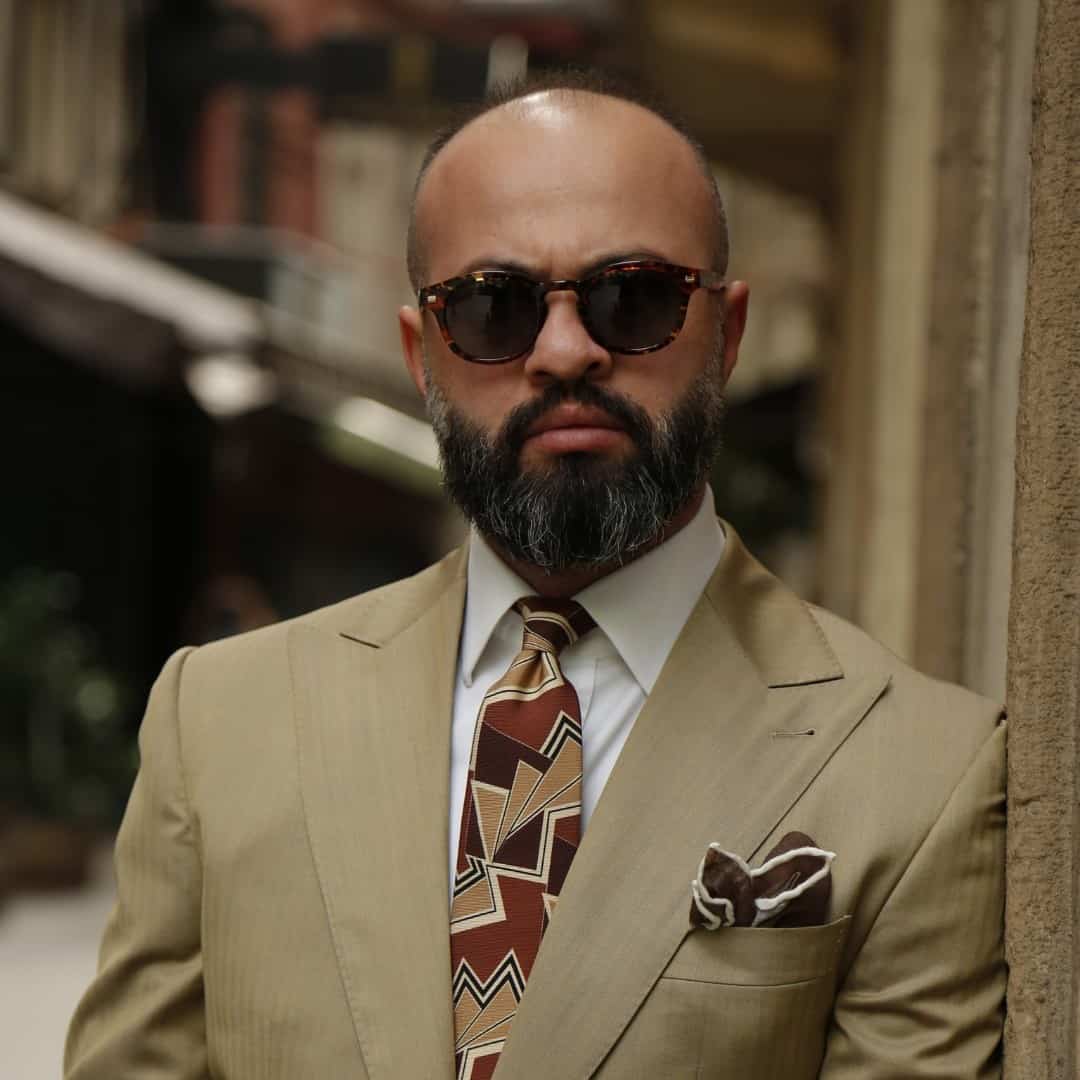 bald man in brown suit wearing sunglasses