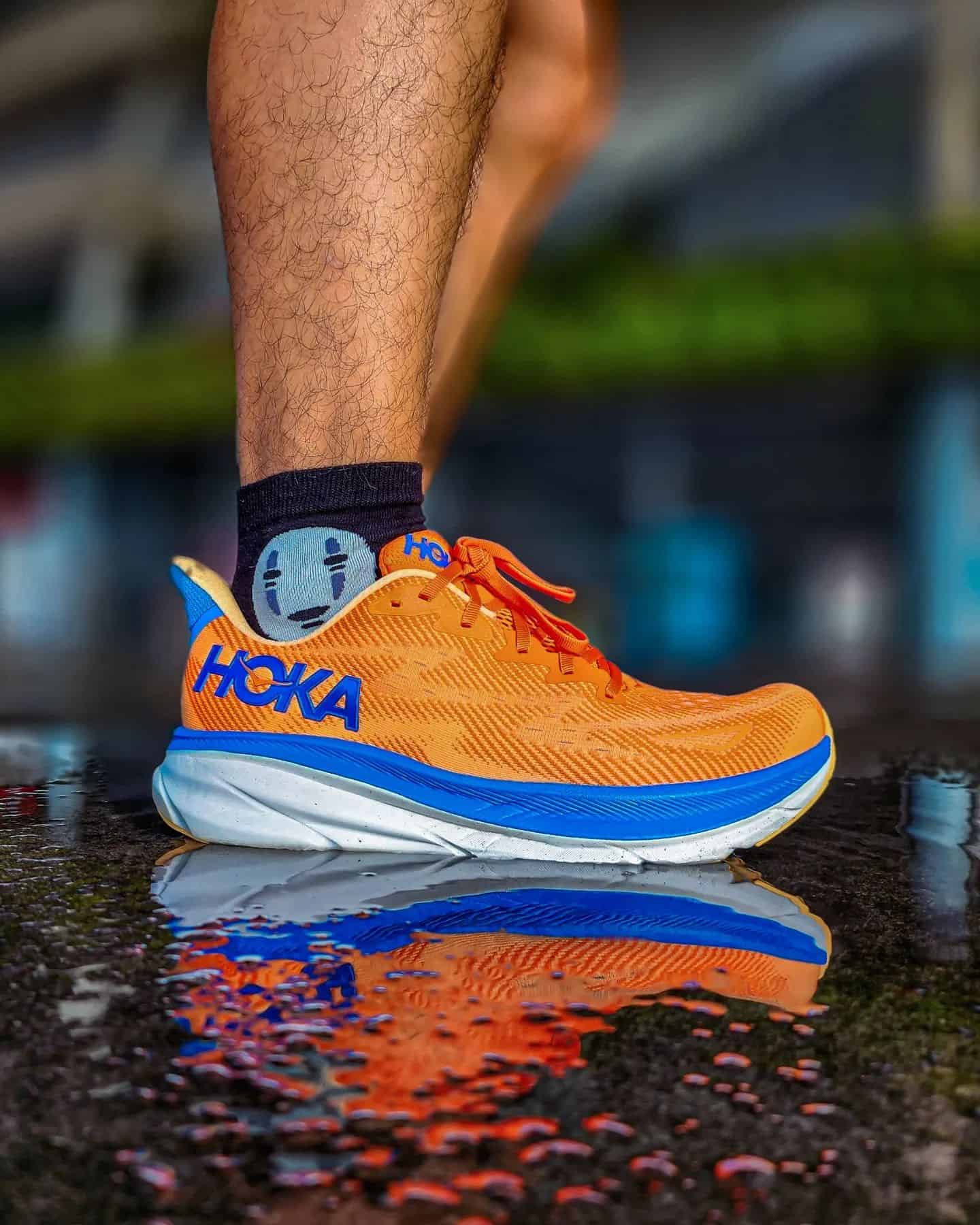 man standing on a puddle wearing the hoka clifton 9 sneakers