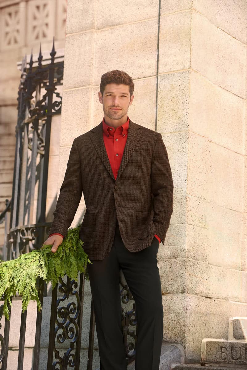 man wearing a red shirt, brown blazer and black pants