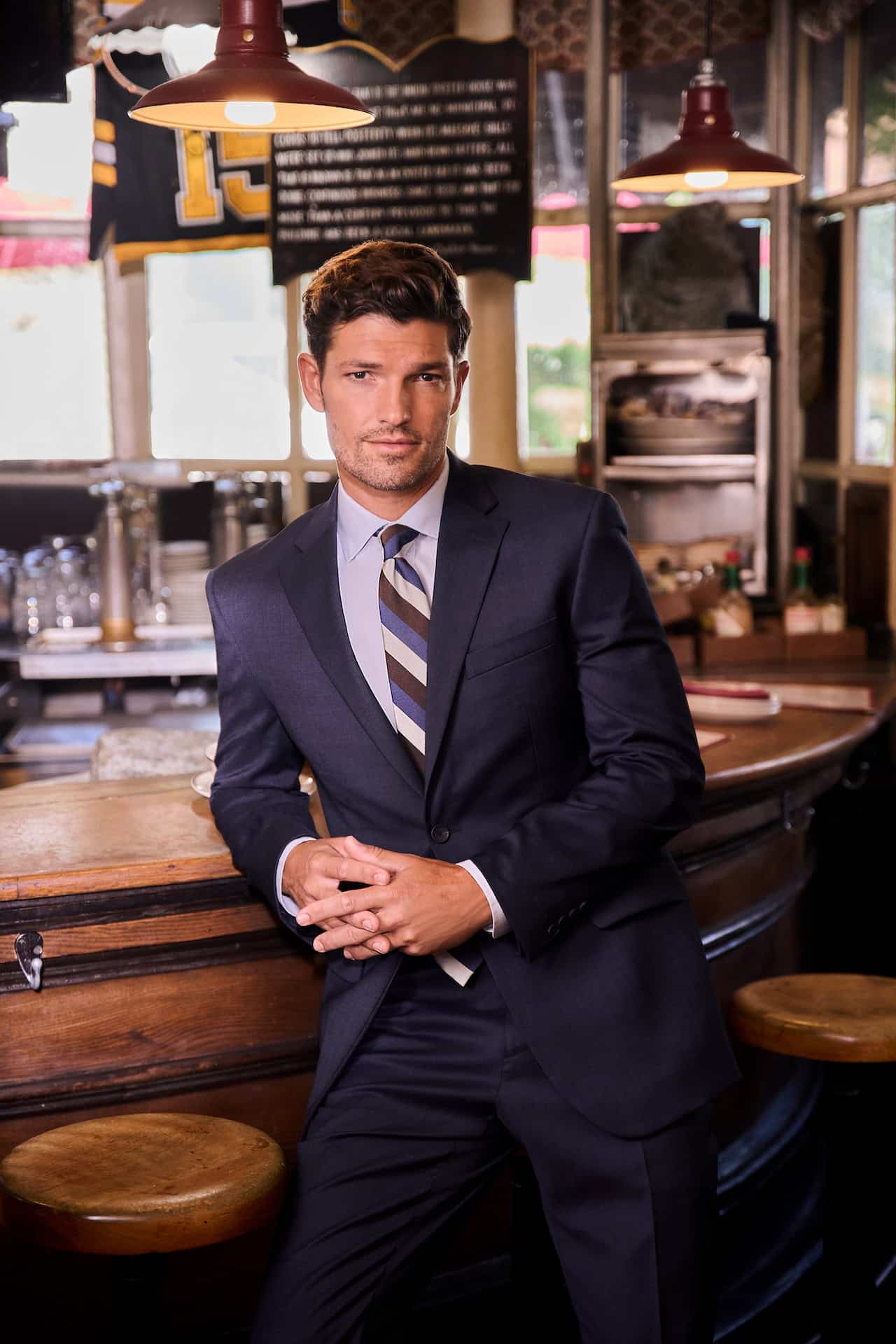 man in a navy suit leaning on a counter at a bar