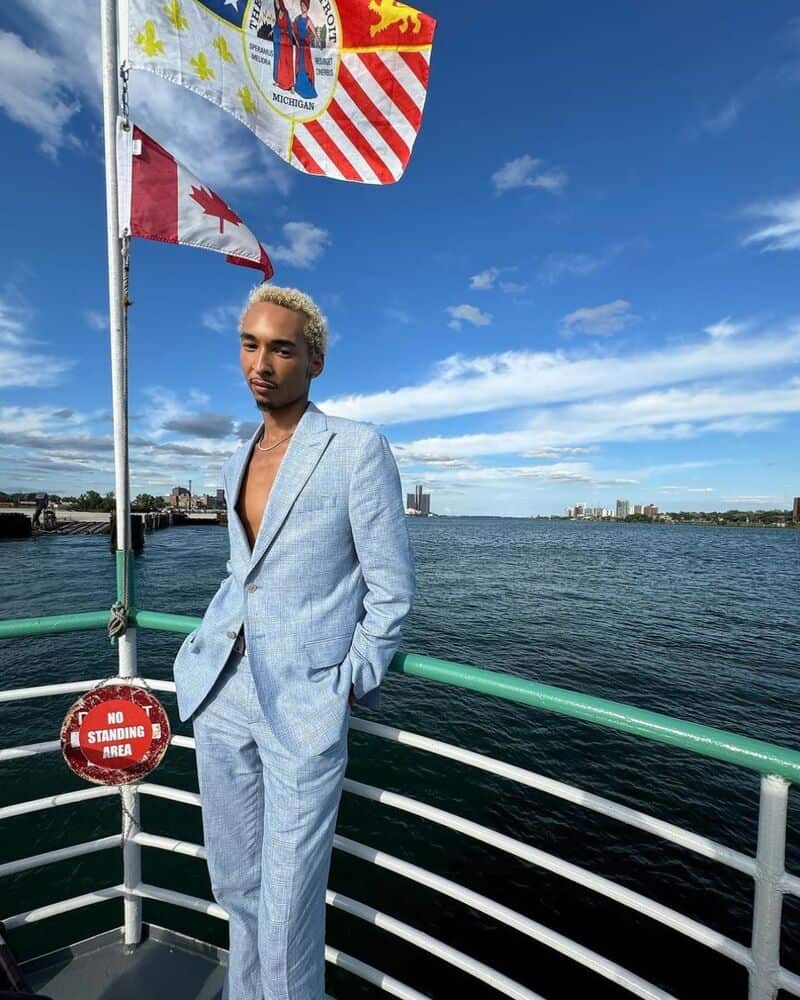 man in a light blue suit standing on the deck of a ship