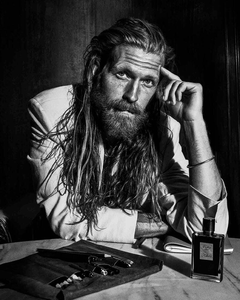 man with long hair and beard sitting infront of a round table