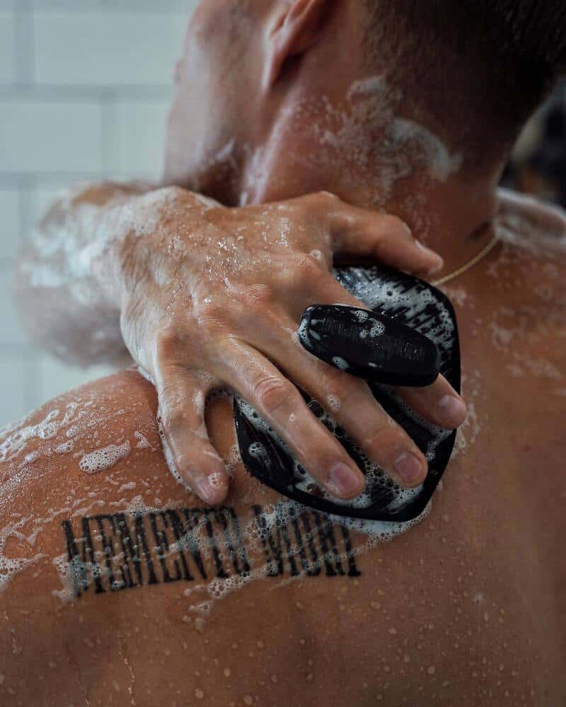 A man scrubbing his back with the Manscaped scrubber