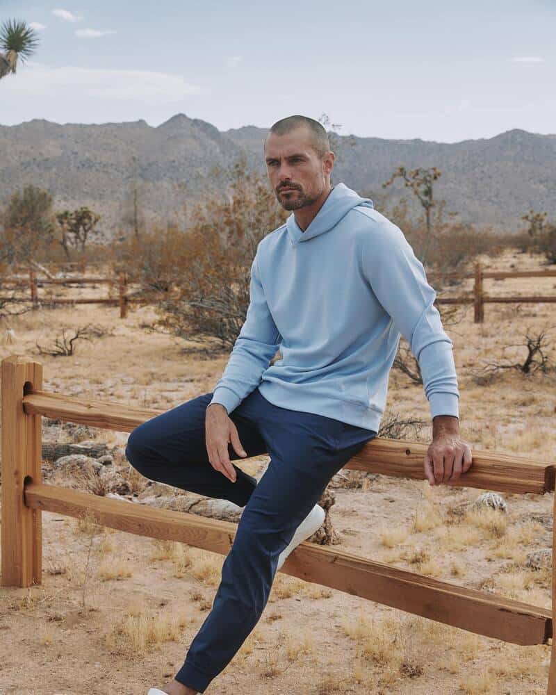 man wearing a 7diamonds hoodie and sitting on a wooden fence