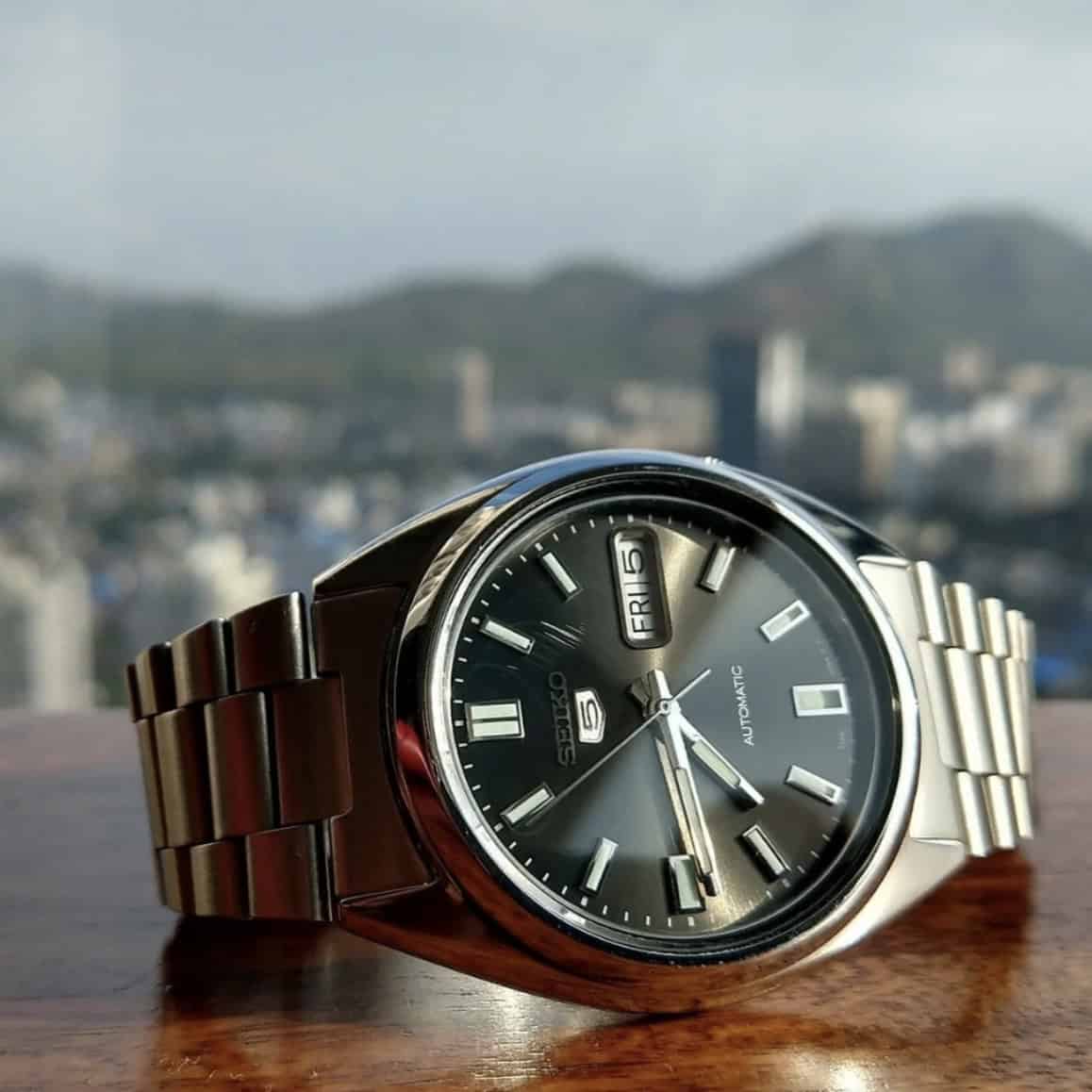 Close up of a Seiko with a city skyline in the background