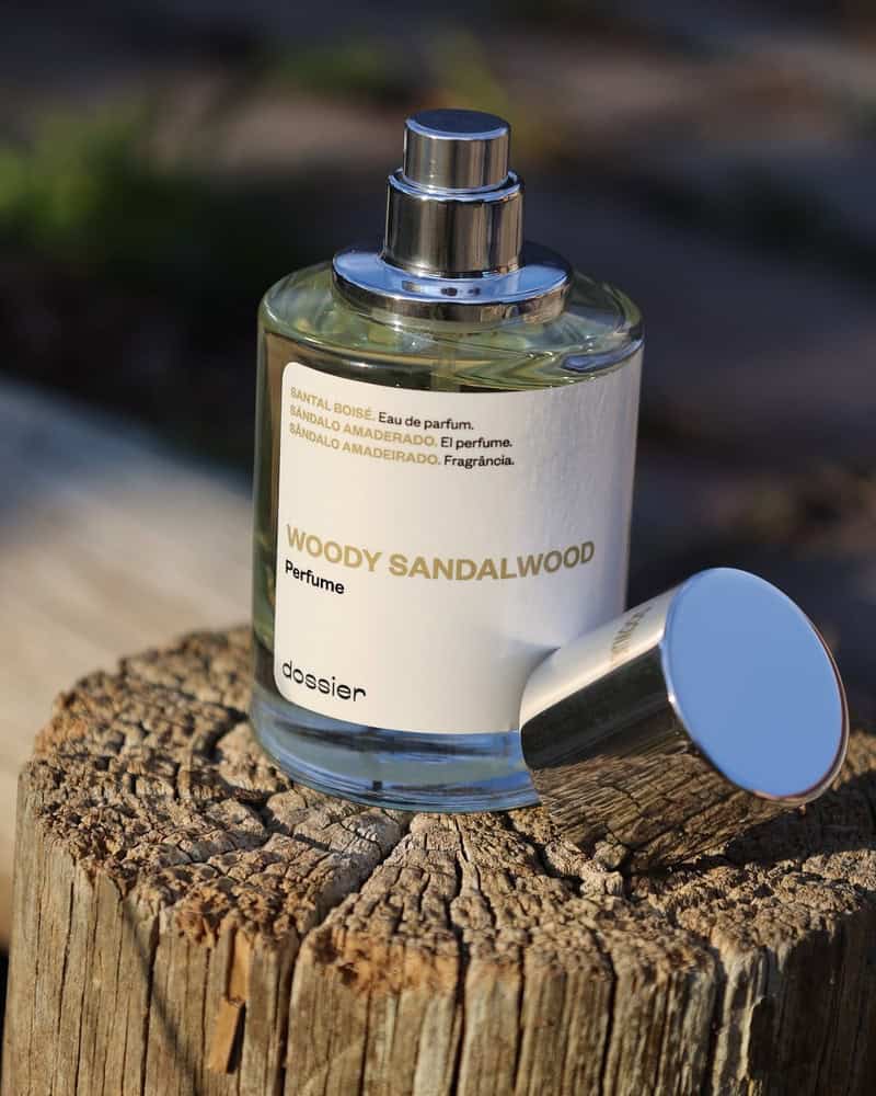 a bottle of Woody Sandalwood Perfume by Dossier on top of a wood post