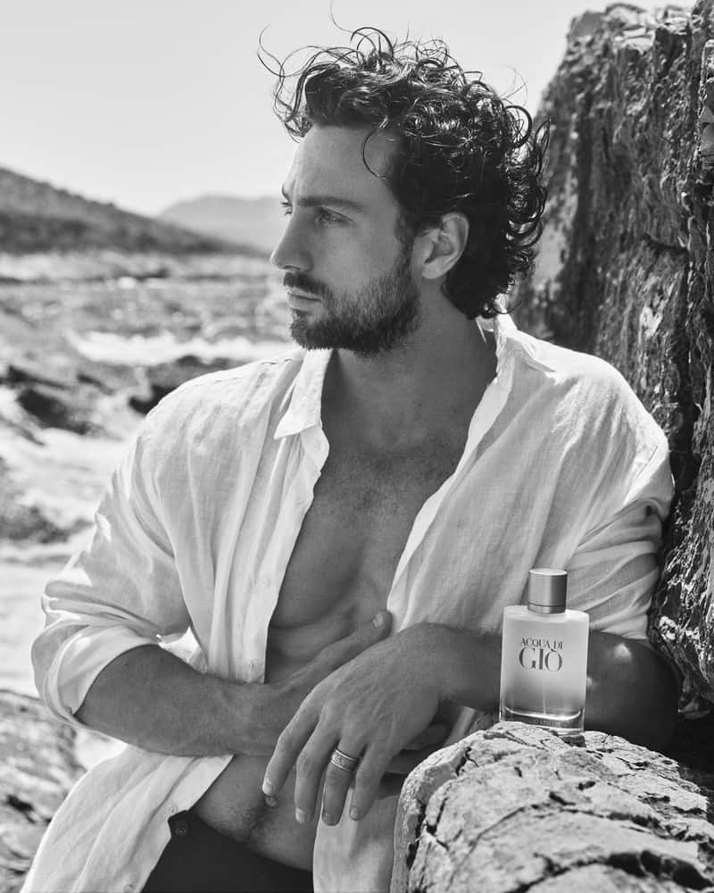 man at the beach with a bottle of Acqua Di Gio cologne beside him