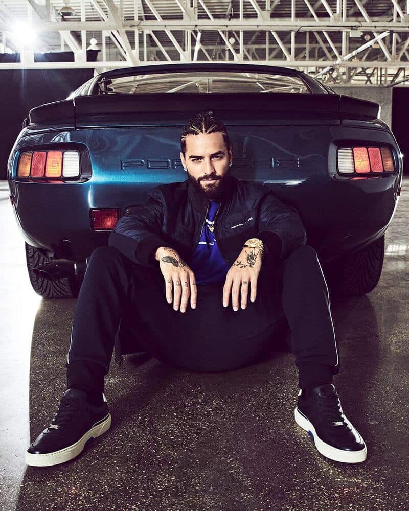 man sitting on the ground at the rear end of a Porsche 928