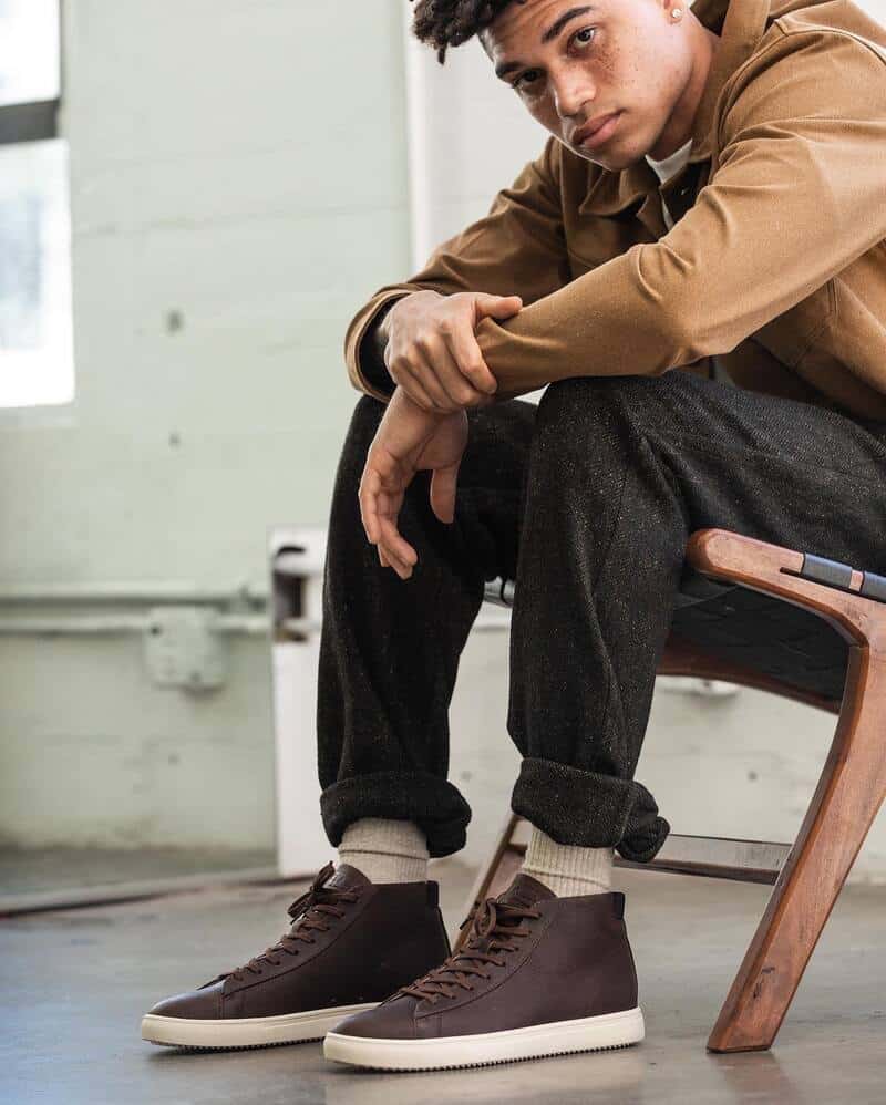 man sitting on a chair wearing the brown mids bradley by clae