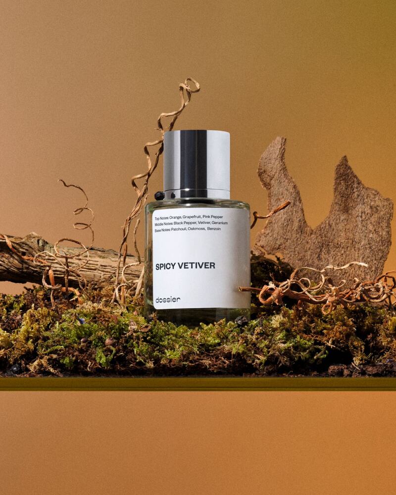 a bottle of Spicy Vetiver Perfume by Dossier on a moss and pieces of wood at the back