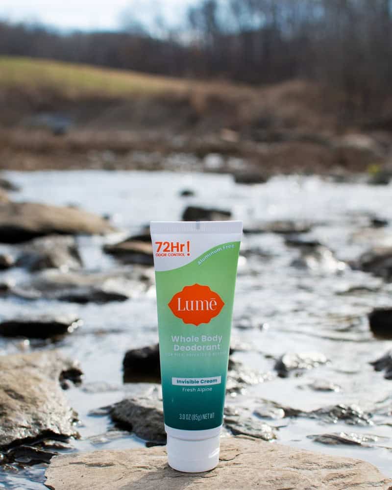 a tube of lume deodorant on top of a rock by the river