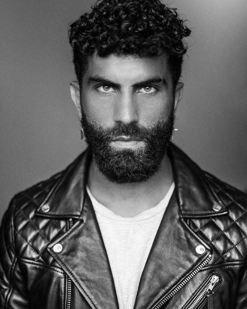 man full beard and curly hair wearing a black leather jacket