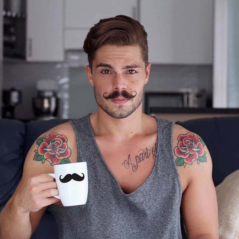 man with a handle bar style mustache holding a cup