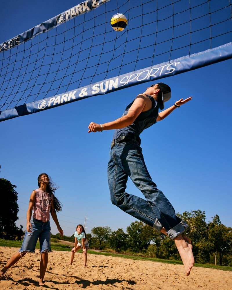 barefoot man in jeans playing volleyball