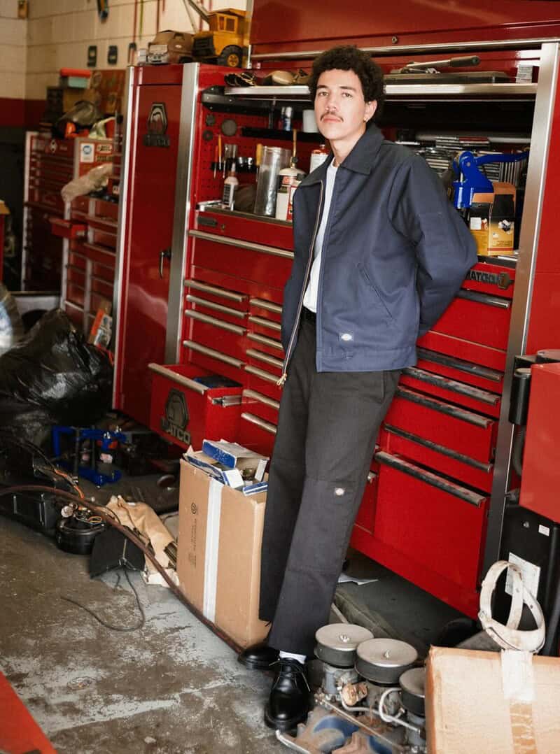 man with a blue jacket and black pants leaning to a tool cabinet