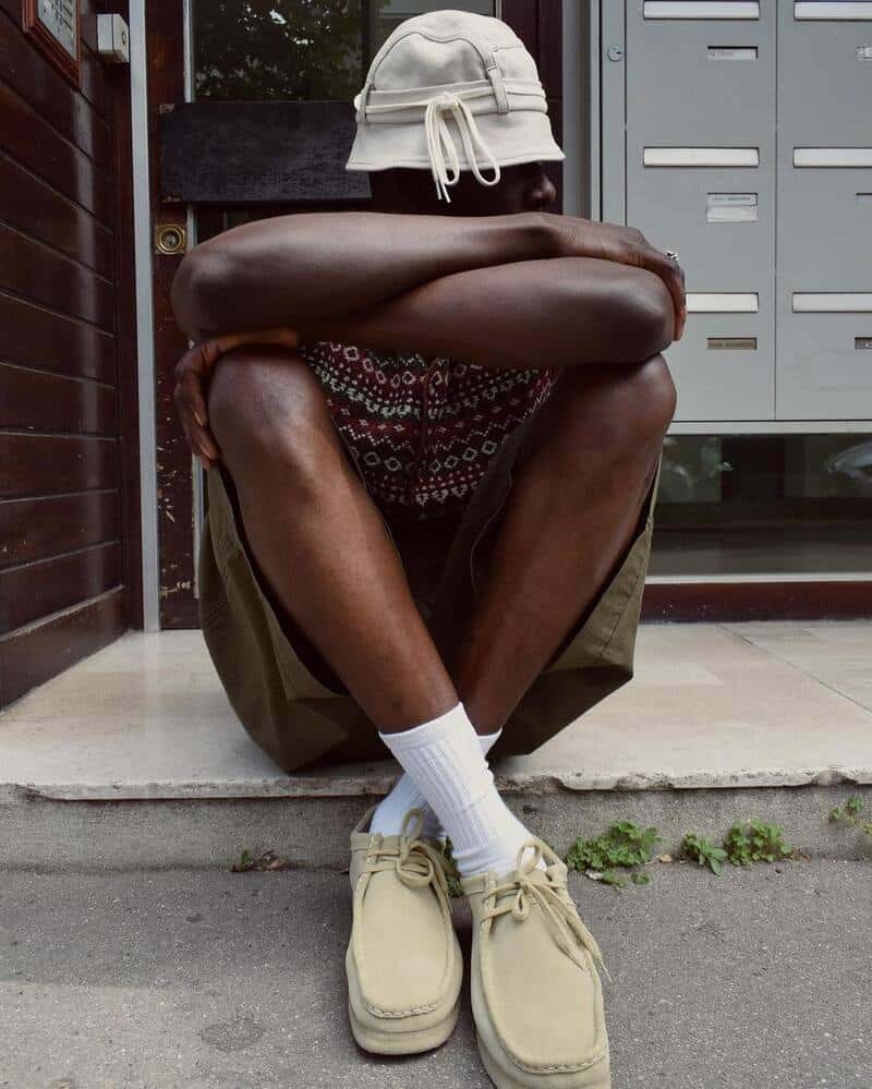 man sitting down on a pavement wearing a wallabee by clarks